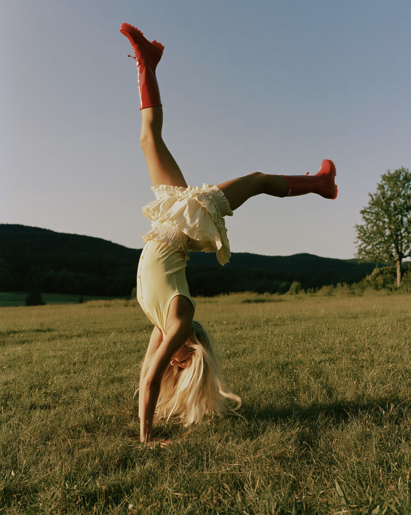 Sunlit fashion image in a meadow with red boots