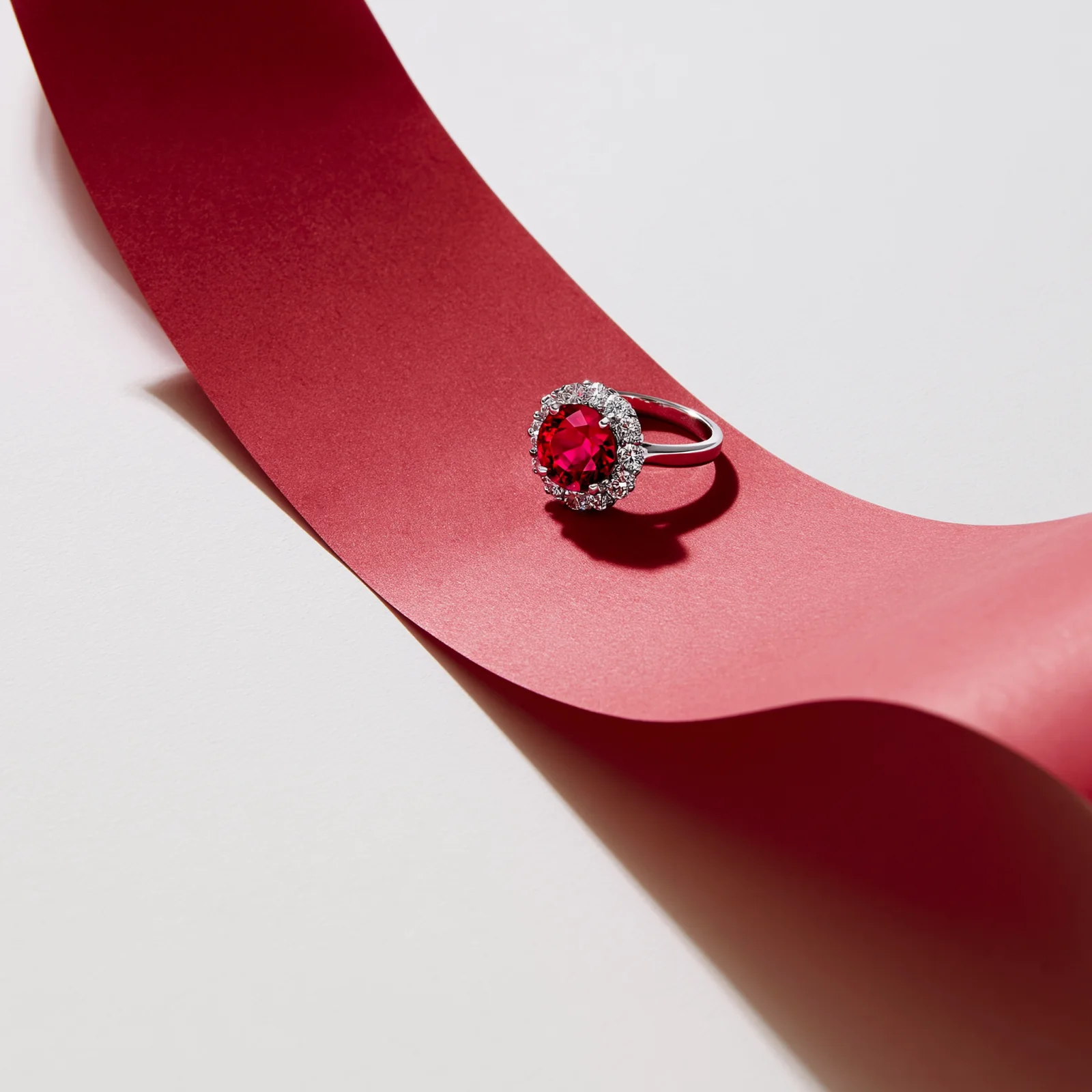 Ruby ring placed on a long red ribbon in a jewelry still life