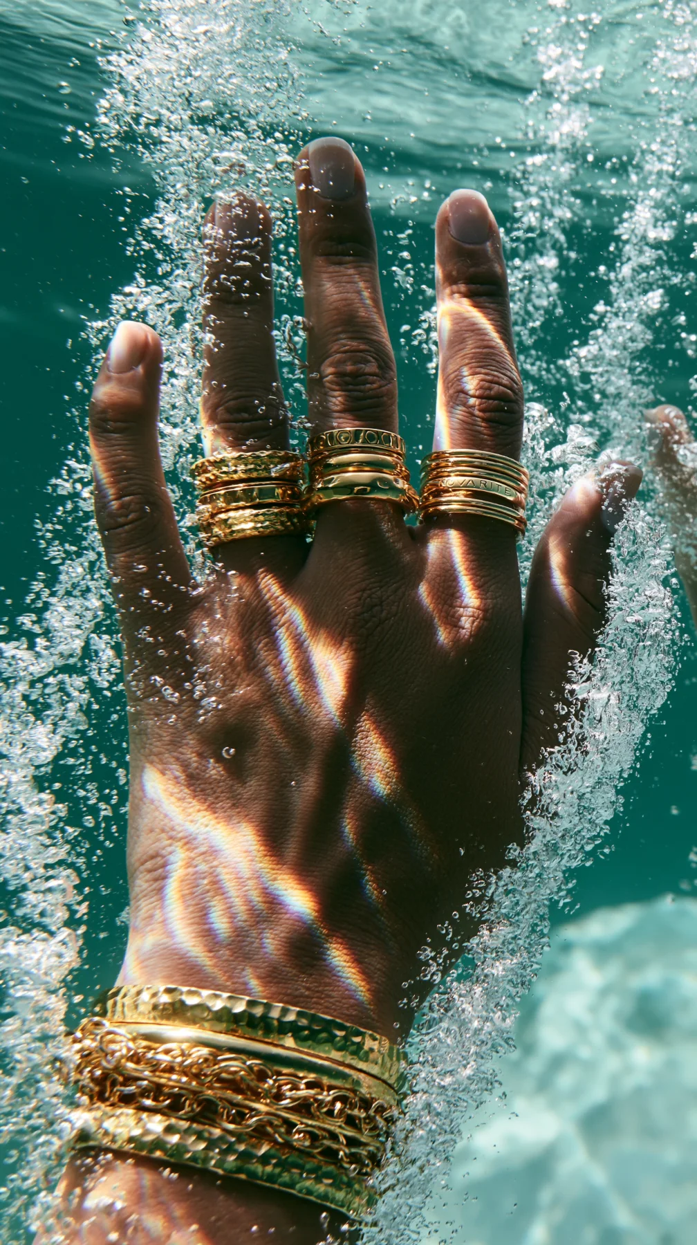 Underwater jewelry campaign image with hand submerged and gold rings